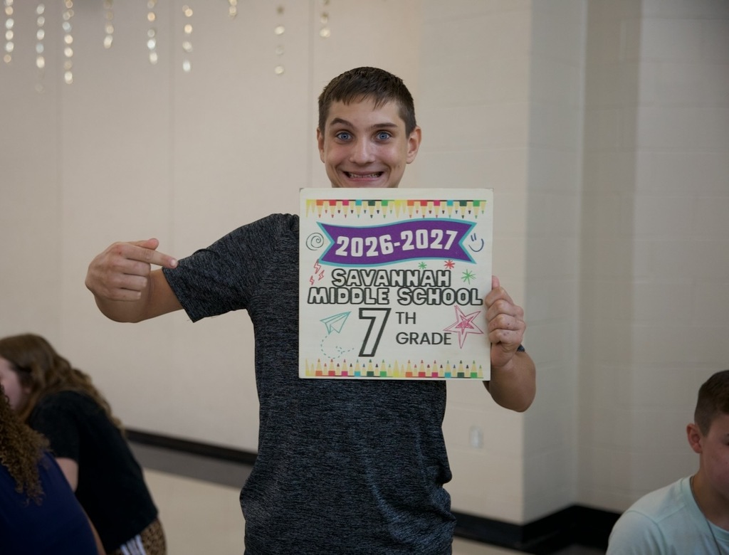 Seventh-grade student grins while holding a Savannah Middle School first-day sign.