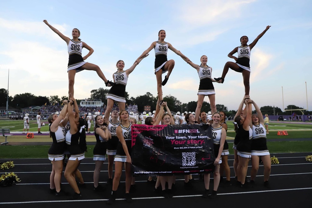 Savannah High School cheerleaders perform stunts on the track during a Friday night football game.