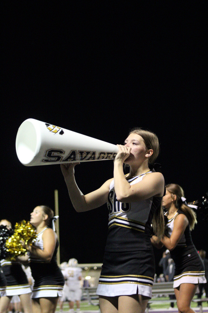 Savannah High School cheerleader cheers through a Savages megaphone under the Friday night lights.