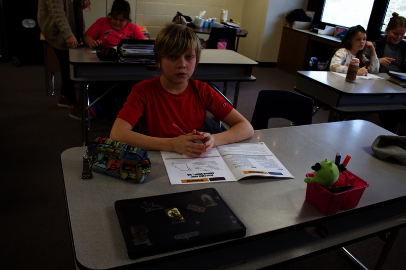 A fifth-grade student sits at a desk with a workbook and pencil during the Junior Deputy Program.