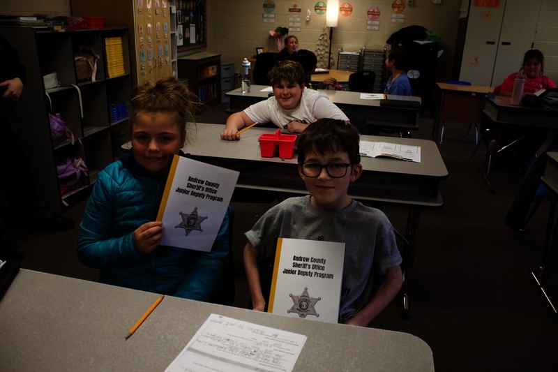Two students hold Junior Deputy Program booklets from the Andrew County Sheriff’s Office.