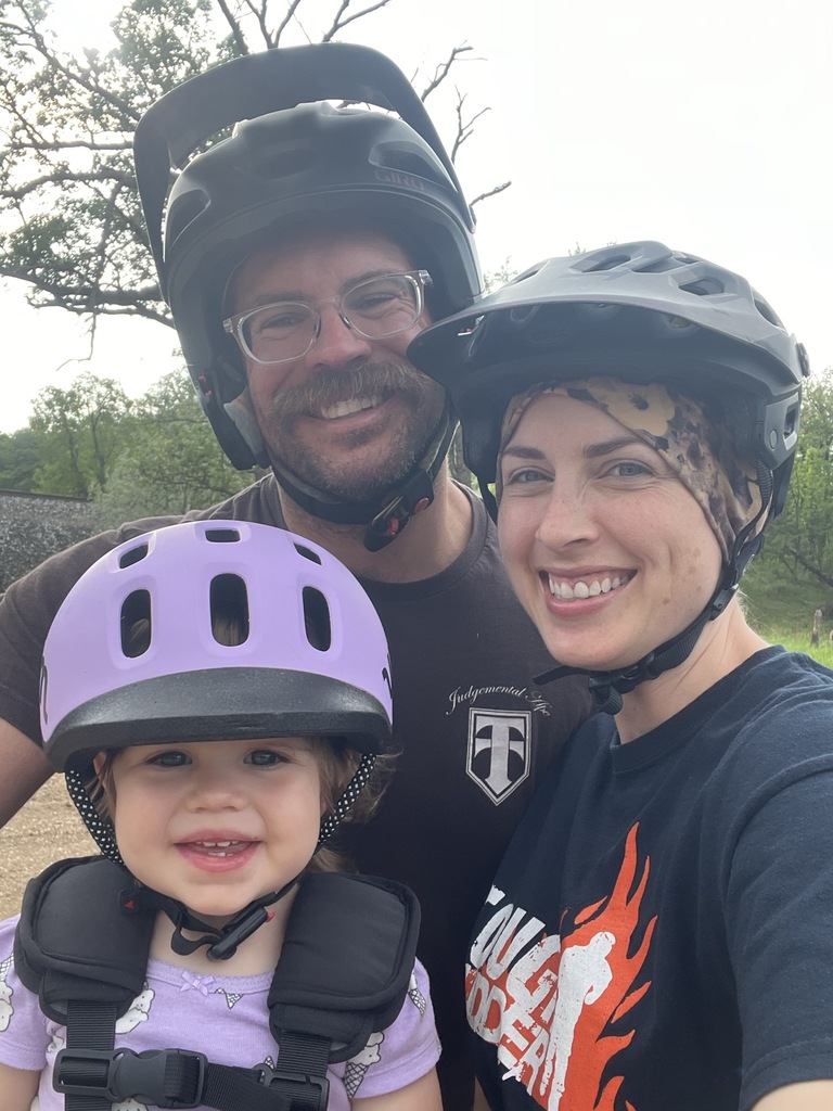 Principal Stockie with his wife and child wearing biking helmets.