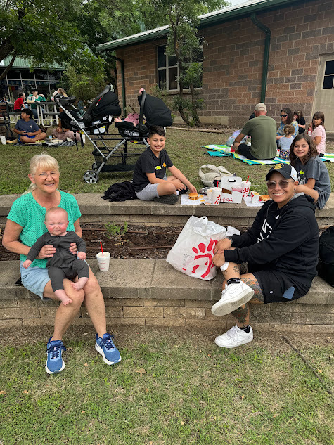 students and loved ones having a picnic style lunch at school.