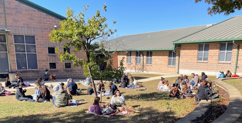 students and loved ones having a picnic style lunch at school.