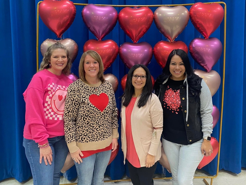 Kindergarten teaching Team posing in front of heart balloon photo backdrop. 