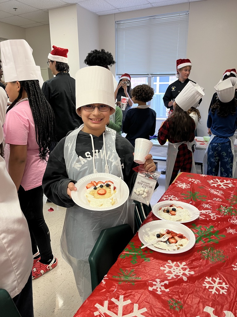 Students cooking pancakes assisted by the high school culinary department.