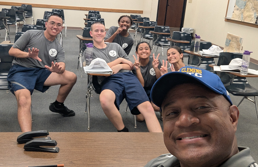 afjrotc cadets & instructors relax inside a classroom setting, smiling for the camera