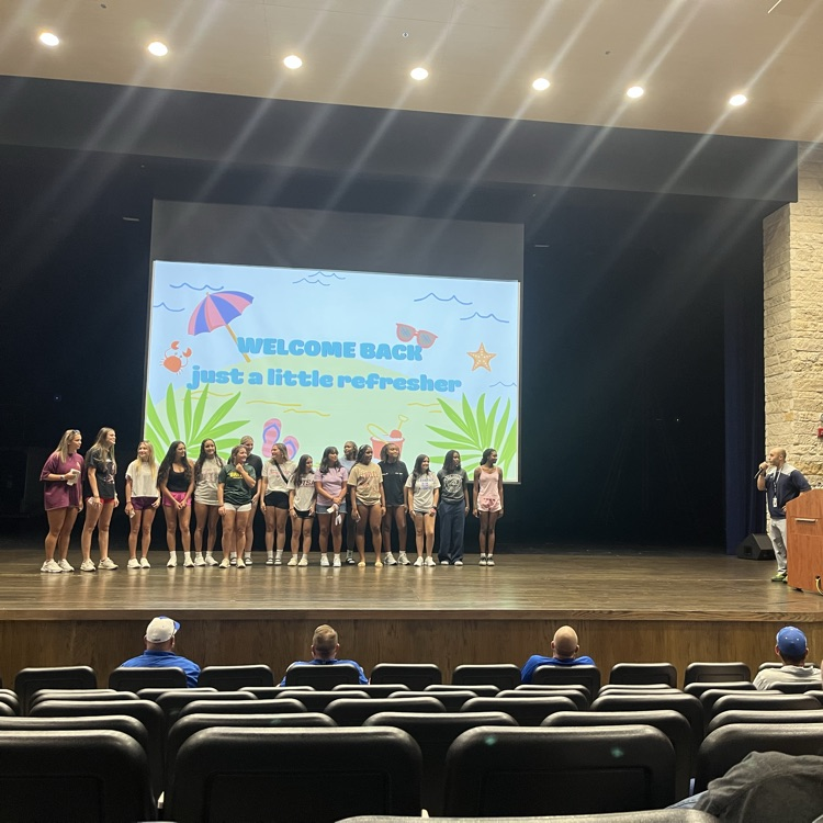 lady buffs volleyball team stands on an auditorium stage before a display screen that reads "just a little refresher"
