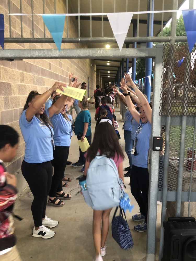students being greeted by teachers on their way into school