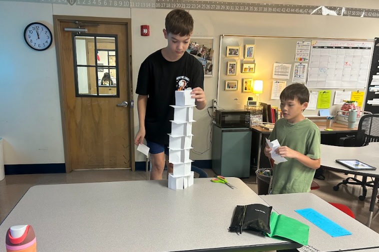 two boys building paper tower