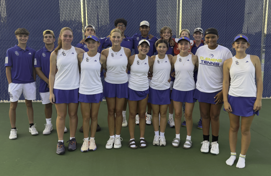 tennis players in blue & white kit stand on a tennis court, smiling after a victorious tournament
