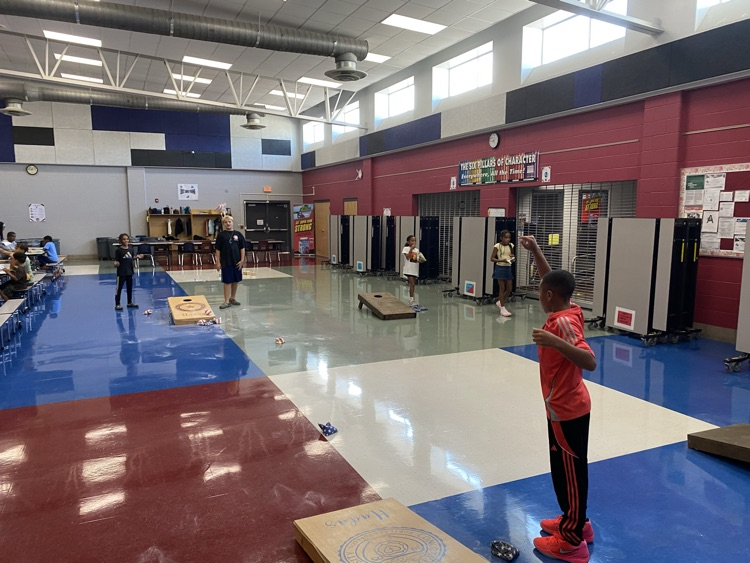 students playing with grandparents in the cafeteria, corn hole