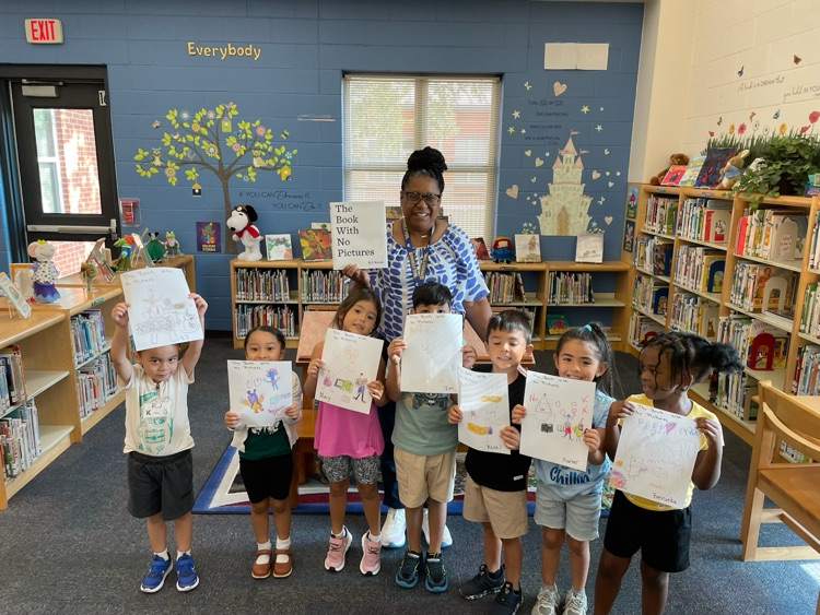 Students posing with a book and their drawing