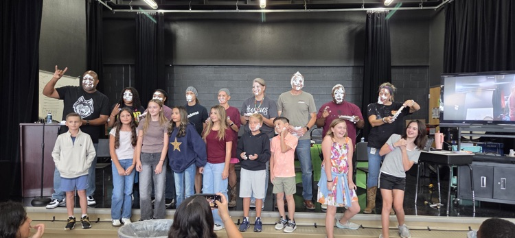 students and teachers lined up on the stage posing with on their face