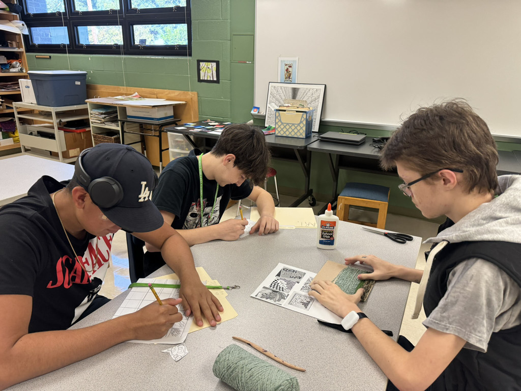 three students drawing in art class