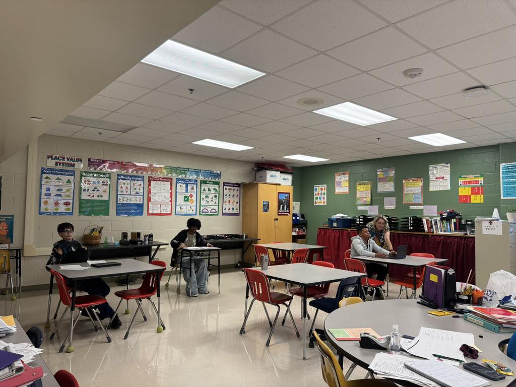 teacher working with student and two students working independently