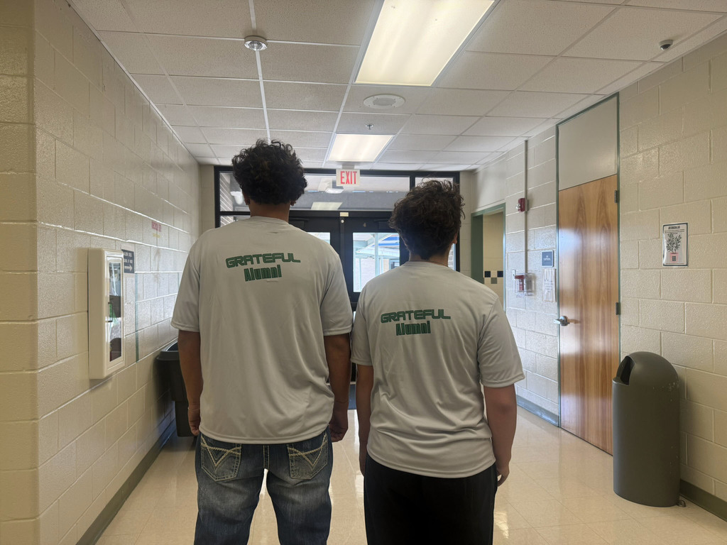 two alumni posing with their alumni shirts