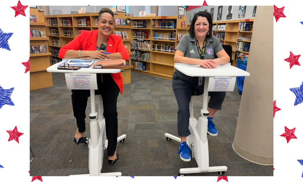 Mrs. Deanna Jackson and Mrs. Paige Meloni on pedal desks in the Corbett library