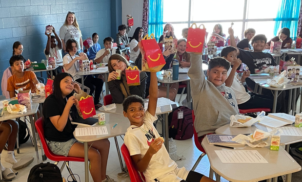 Students holding up McDonald's breakfast items in a classroom