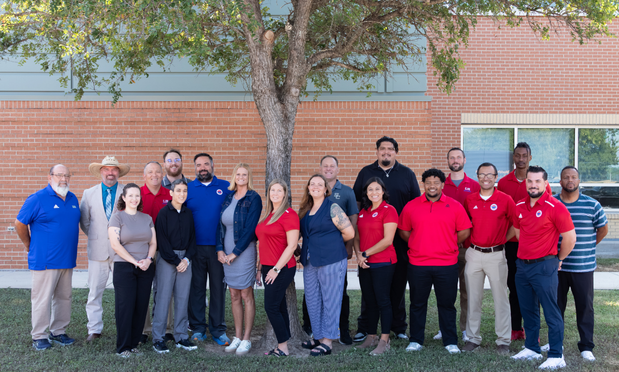 A group of coaches standing in front of a tree in a group photograph