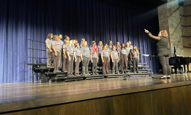 Choir students and choir director on risers during their performance