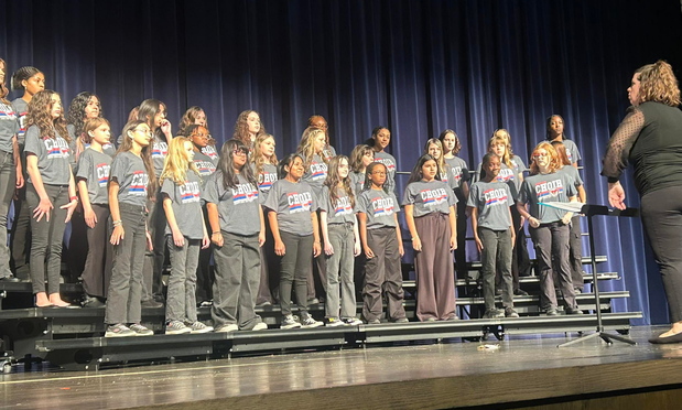 Choir students and choir director on risers during their performance