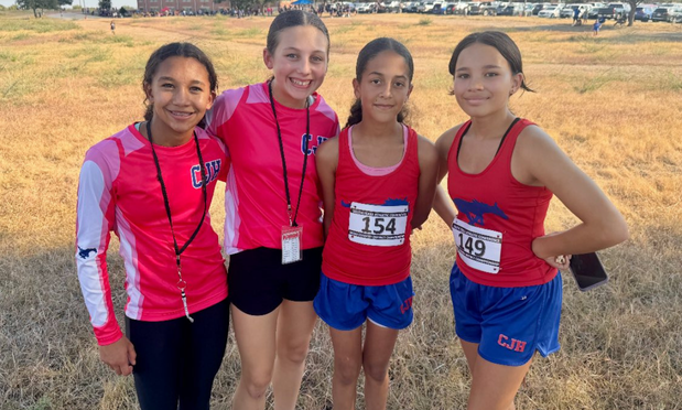 A group of four girls cross country athletes at a meet