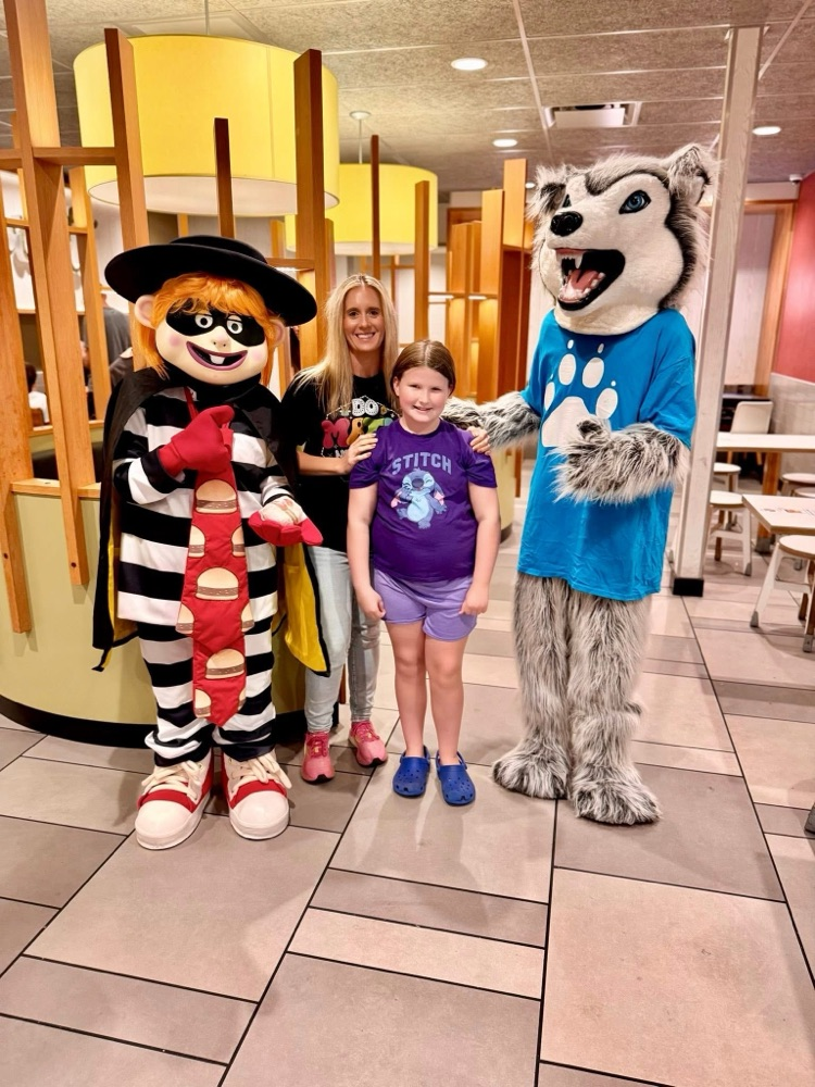 hamburger, Miss Housley, a student the Husky mascot all posing at McDonald’s