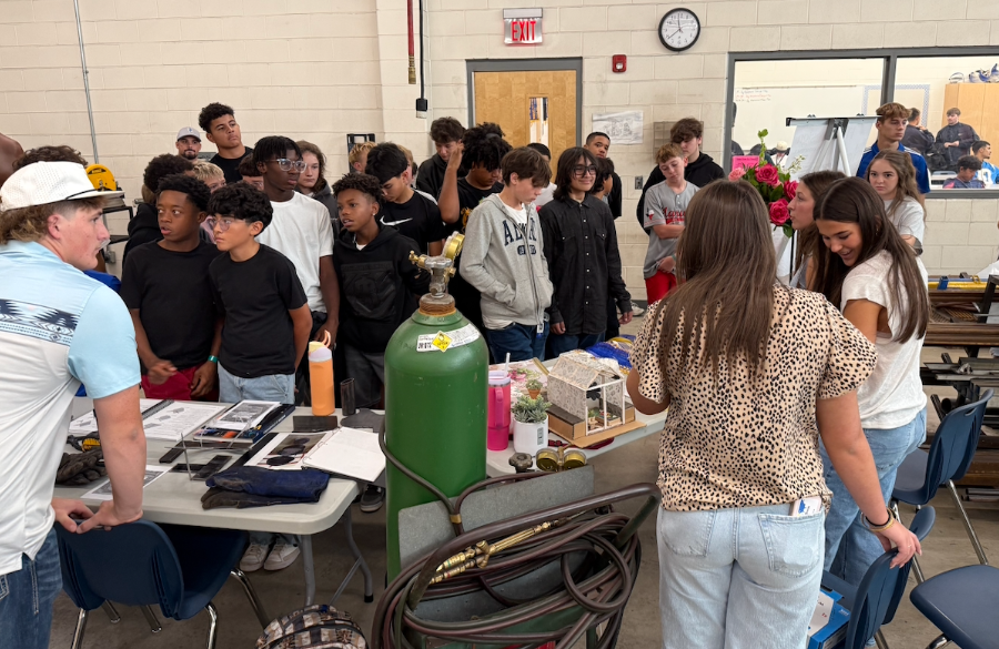 junior high students in a large classroom interior observe career & technology education presentations offered by high school students