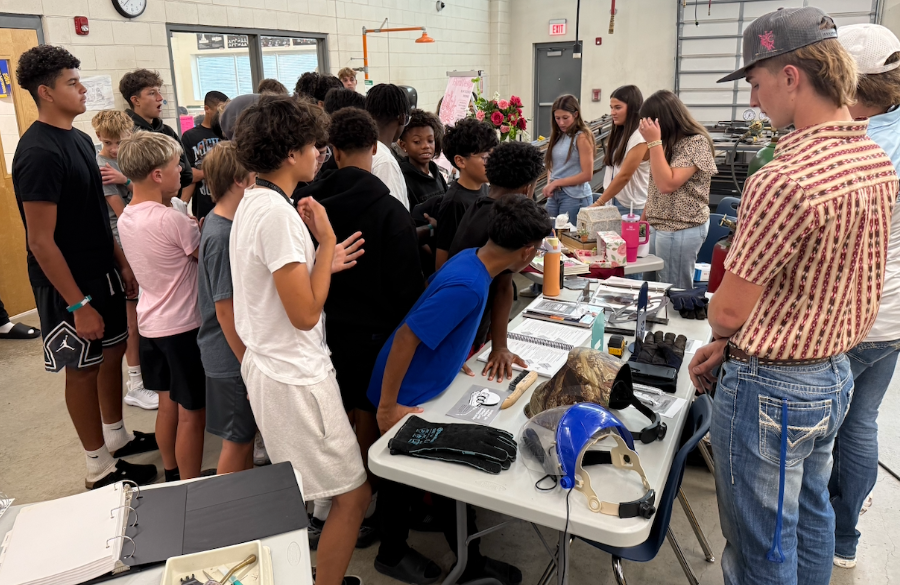 junior high students gather in a classroom, viewing equipment utilized in welding