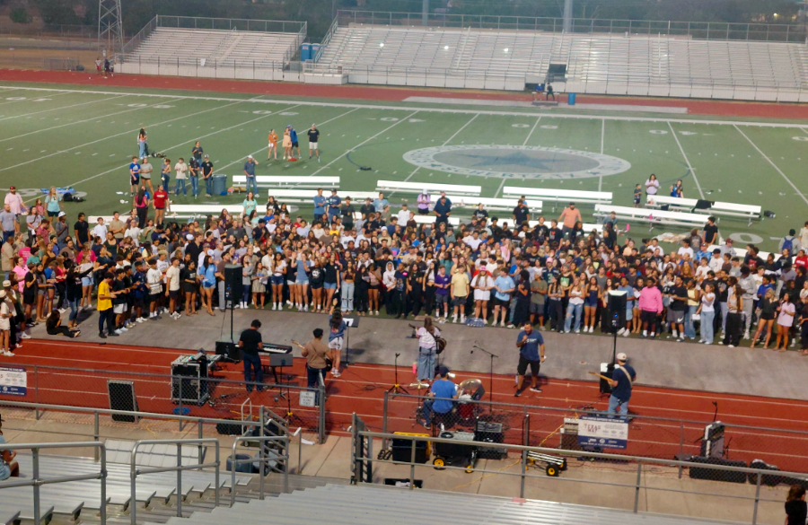 high school students surround a live band on a football field