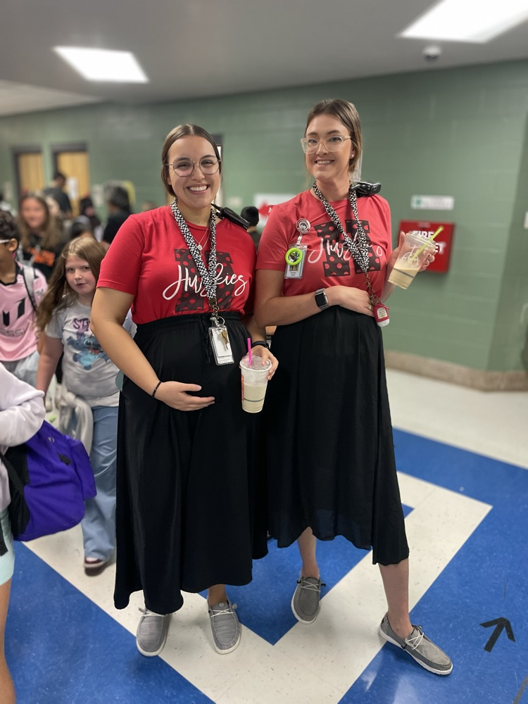 Two staff members posing as twins in the hallway