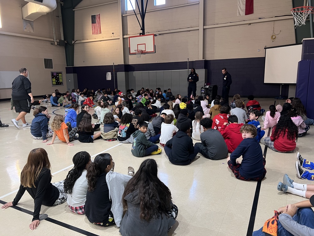 6th graders in the gym listening to firefighter presentation