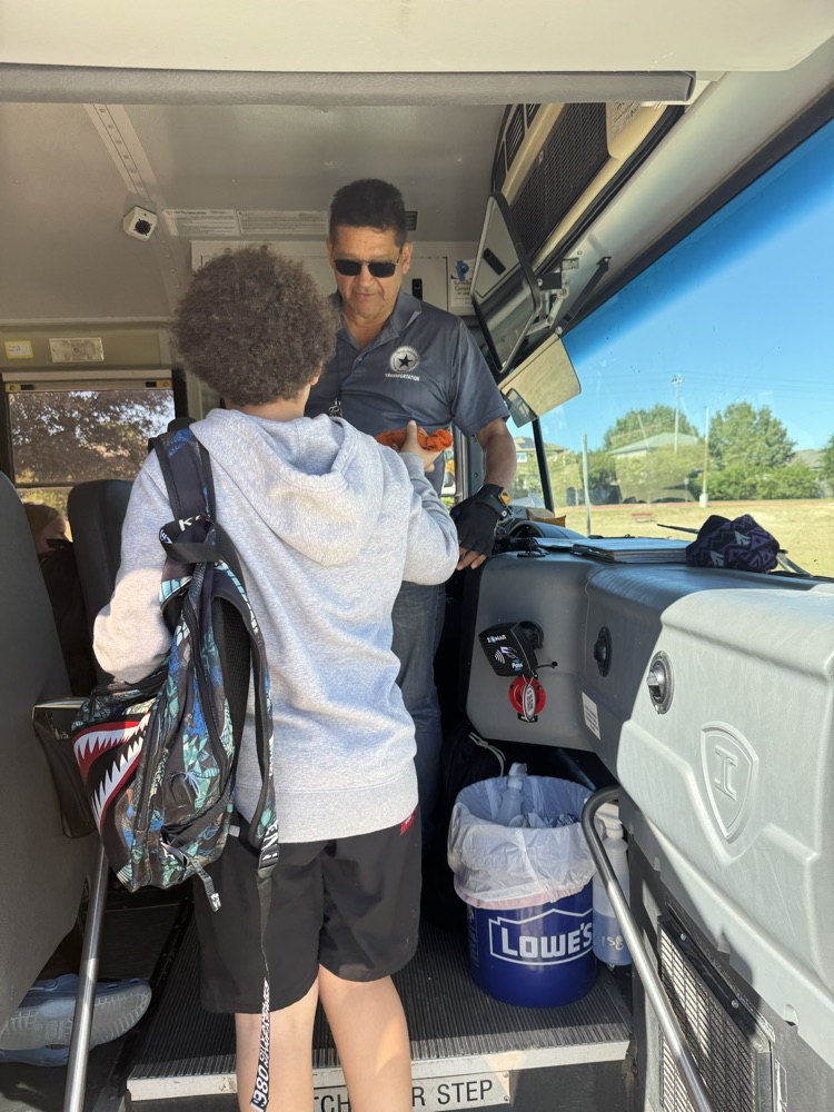 student handing a gift to a bus driver