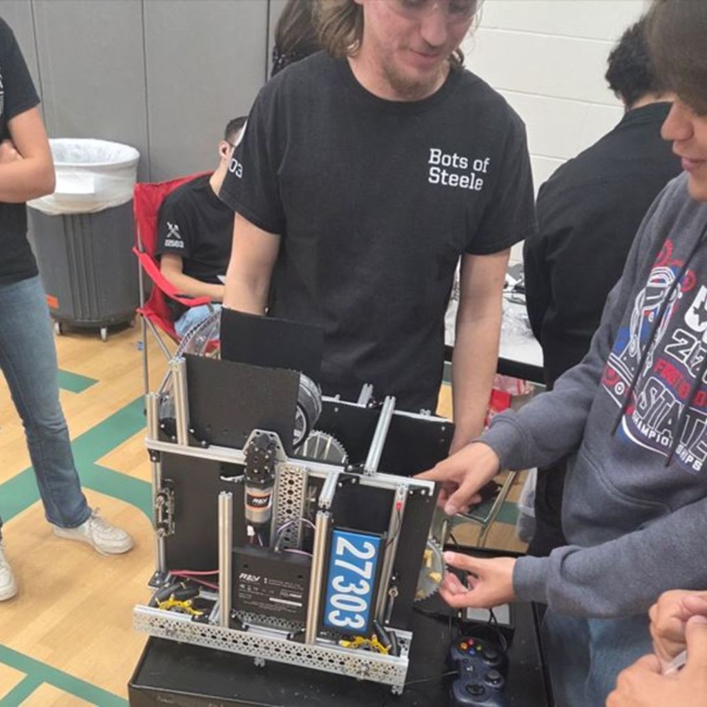 A student discusses their winning robot with another team.