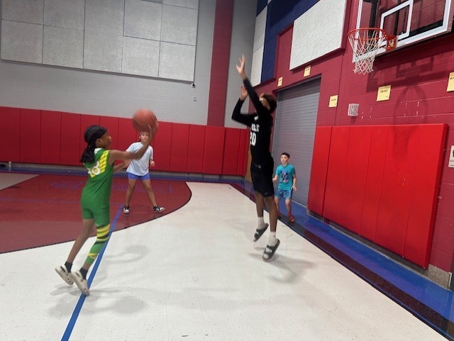 Students playing basketball with a high schooler