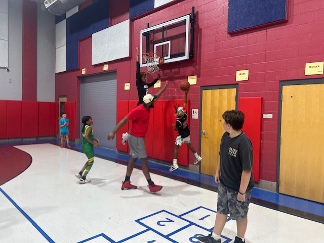 Students playing basketball with a high schooler