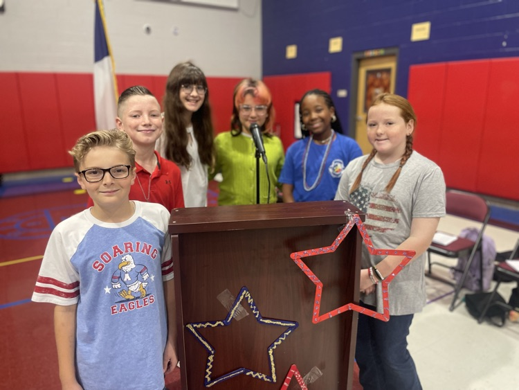 We serve two speakers posing by a podium two boys for girls