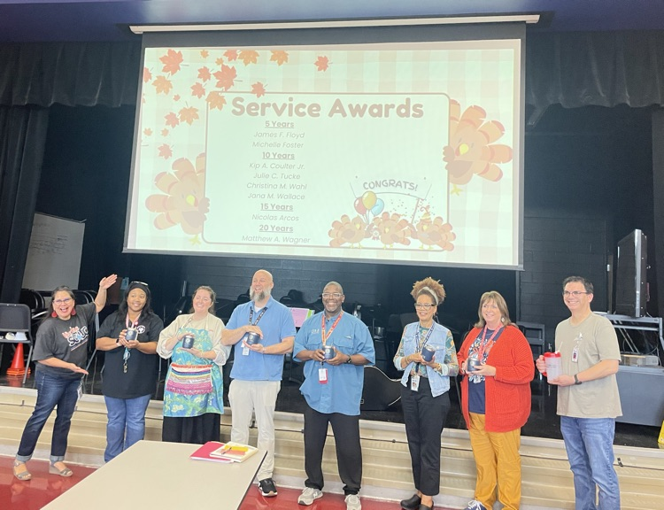 teachers standing for their service awards and award cups