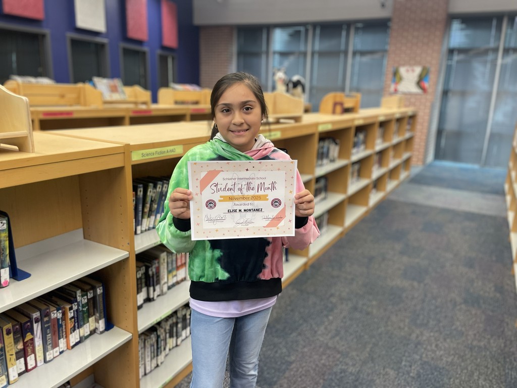 6th grade student with her award in the library
