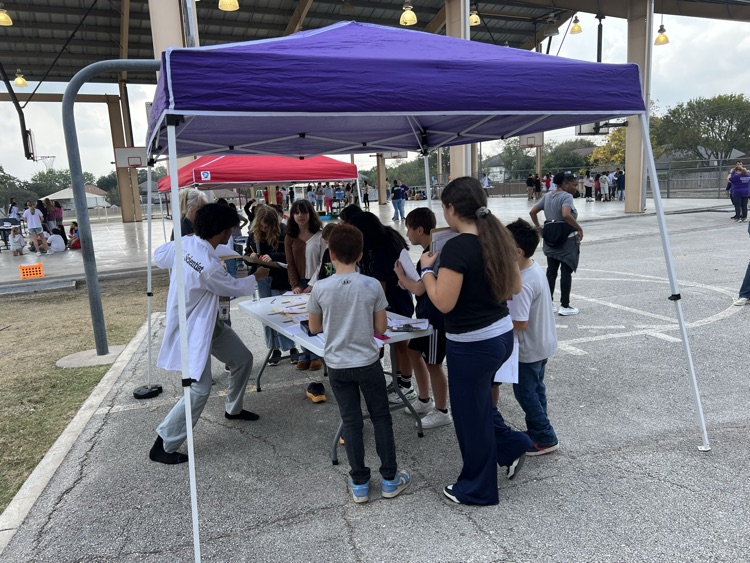 students under canopy listening to science lesson