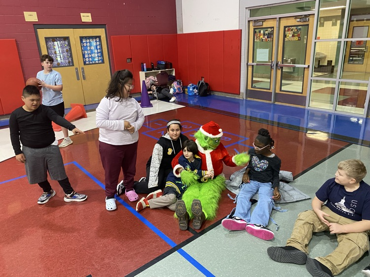 students in gym sitting with the grinch