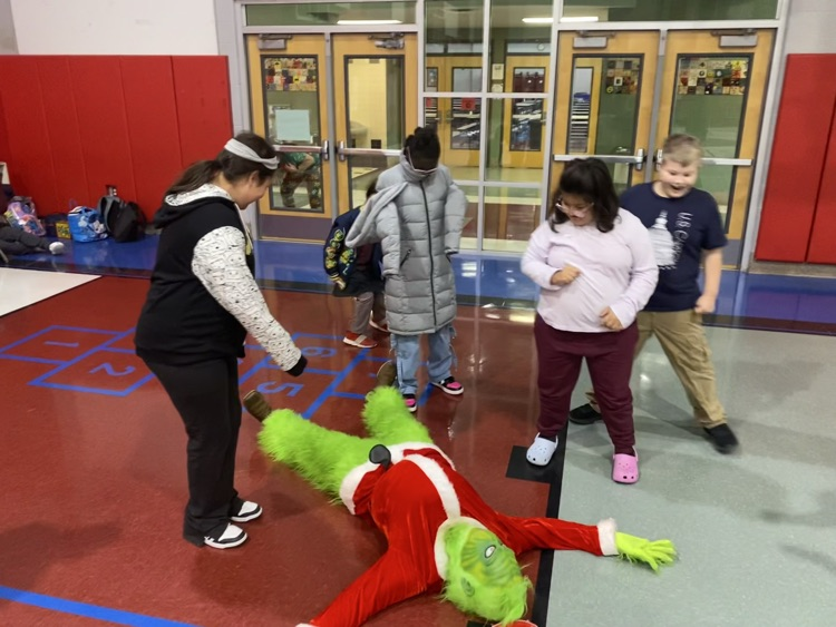 students pointing at the grinch who’s laying on the floor