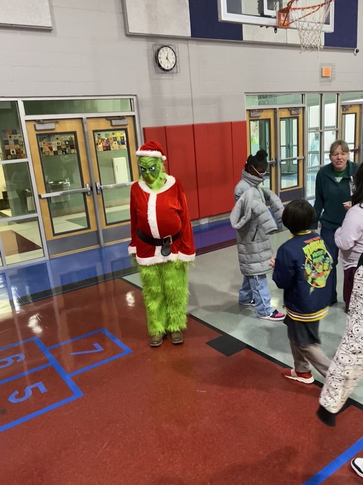 the grinch staring at the camera while the kids play in the gym