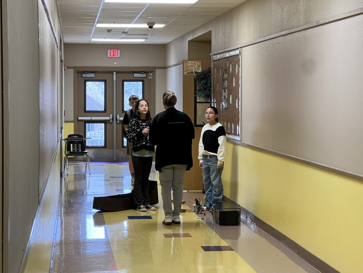 students getting guidance from their teacher in hallway