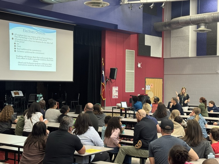 Ayshan parents sitting in the cafeteria, listening to presentation