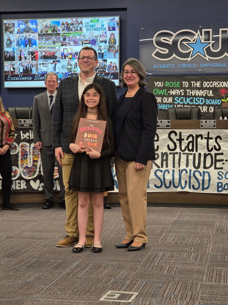 Mr. Piles and a 4th grade student present a book to the Board of Trustees