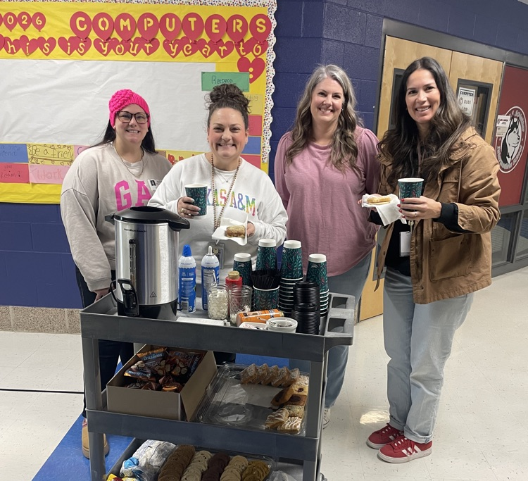 PTC parents and two teachers getting hot chocolate and sweets at the cart in the hallway