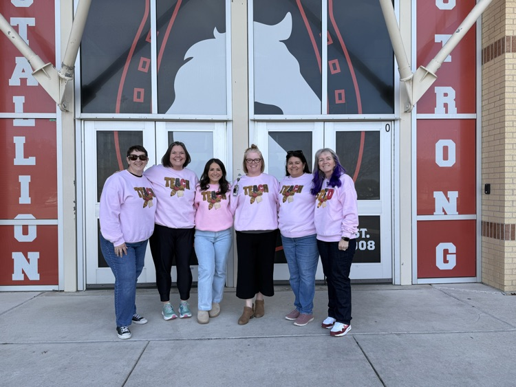 teachers in pink sweaters gifted to them from a family