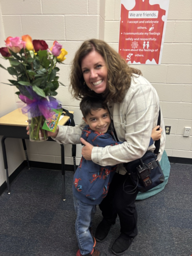students with adult hugging with flowers